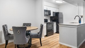 A compact kitchen with a dining area, featuring a round table and four chairs, a microwave, a stove, and a refrigerator. - Beautiful 1BD/1BA in University Hills jkxg (Austin)