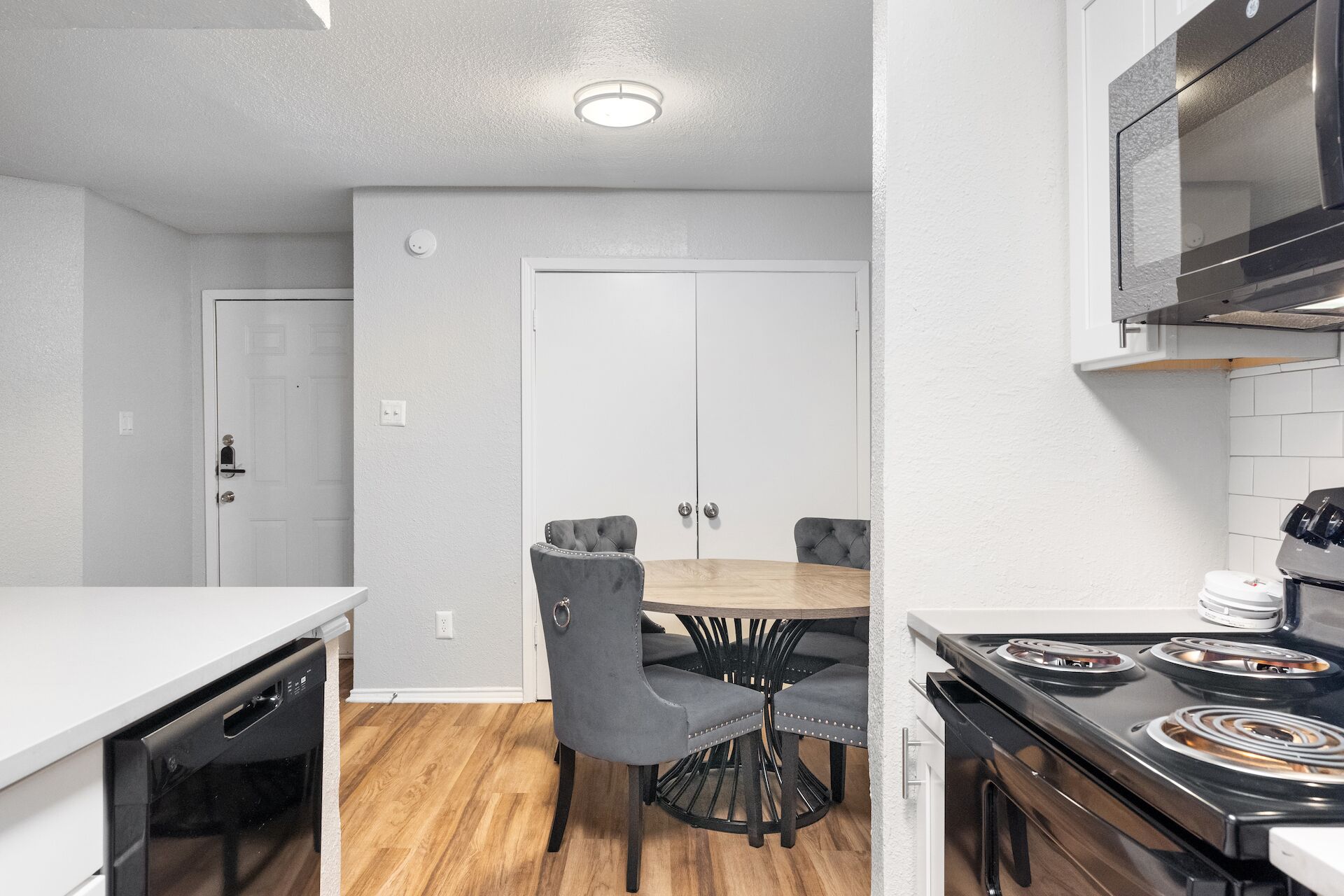 A compact kitchen with a dining table and chairs, a built-in oven, and a microwave.