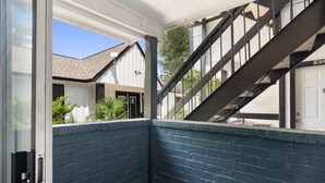 A corner of a building with a blue brick wall, a white door, and a staircase leading to an upper level. - Beautiful 1BD/1BA in University Hills jkxg (Austin)