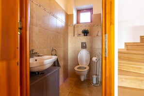 Un baño con lavabo, inodoro y una pequeña ventana sobre el inodoro.