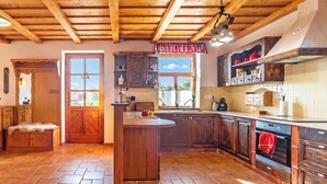 A kitchen with wooden cabinets, a central island, and a window with a view. - Balaton View From Almadi With Terrace & Garden (Balatonalmadi)