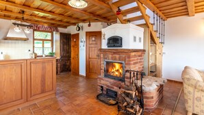 Eine rustikale Küche mit Kamin aus Ziegelsteinen, Holzbalkendecke und einer Holztreppe.