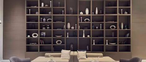 Un salon moderne comprenant un ensemble canapé et deux fauteuils, une table basse et une grande étagère remplie d’objets décoratifs.