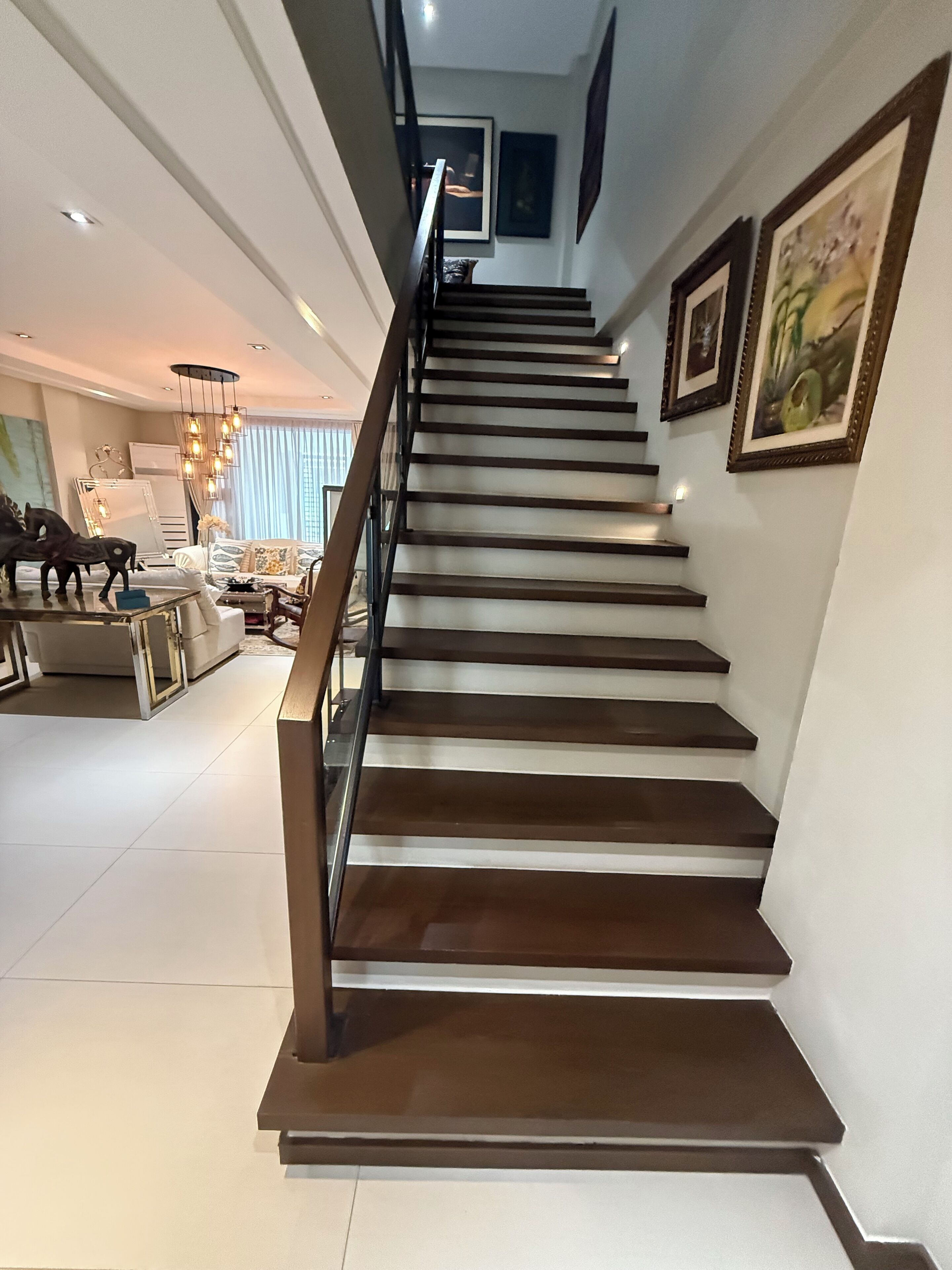 A modern staircase with a metal railing, leading to a second floor.