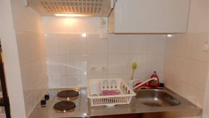 A kitchen with white tiles, a stainless steel sink, and a white dish rack. - Downstairs nature studio (Grenoble)
