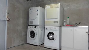 A laundry room with stacked washers and dryers, a sink, and a bottle of detergent. - Downstairs nature studio (Grenoble)