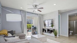 A modern living room with a grey sofa, a white coffee table, and a ceiling fan. - Modern Villa / Movie Room, Private Pool & Spa/10 Mins to Disney + Free WiFi (Kissimmee)