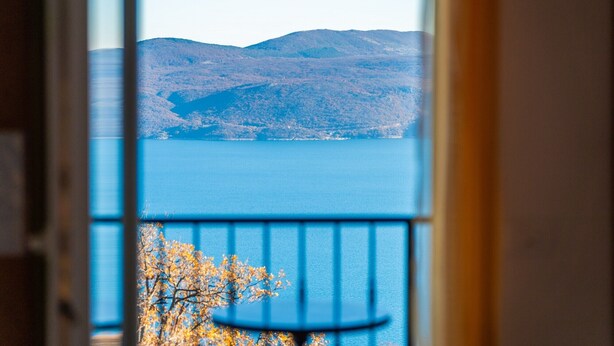 A view from a balcony overlooking a lake with mountains in the distance.