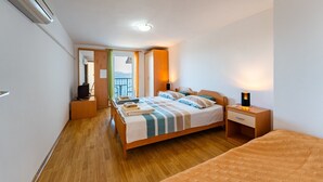 A hotel room with a bed, bedside tables, a TV, and a balcony with a view.