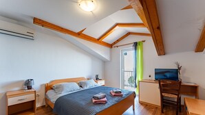 A bedroom with a wooden bed, bedside tables, a desk, and a TV.