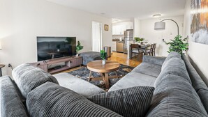 A modern living room with a grey sofa, a coffee table, and a flat-screen TV. - Beautiful 2bd/1.5ba near BU i31b (Boston)