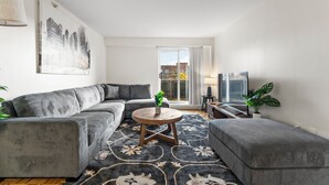 A modern living room with a grey sectional sofa, a round coffee table, and a patterned rug. - Beautiful 2bd/1.5ba near BU i31b (Boston)