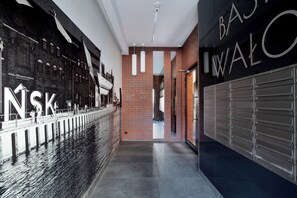 A modern interior with a brick wall, a metal railing, and a large sign with letters. - Elite Apartments city center prestige (Gdansk)