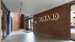 A modern building entrance with a brick wall and a sign reading "AURA 40". - Elite Apartments city center prestige (Gdansk)