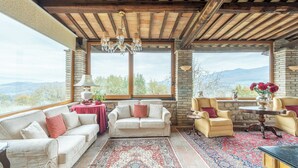 Una habitación acogedora con chimenea de piedra, un ventanal con vistas a la montaña y un candelabro.