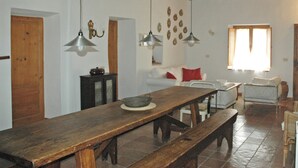 Amplia sala de estar con una mesa de comedor de madera, bancos y un techo alto con vigas a la vista.