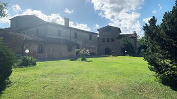 Un cortile con un edificio in pietra, caratterizzato da un ingresso ad arco centrale e un campanile.