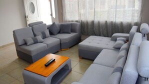 A modern living room with a sectional sofa, a wooden coffee table, and a door leading outside.