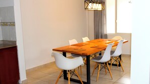 A dining area with a wooden table, white chairs, and a modern pendant light.