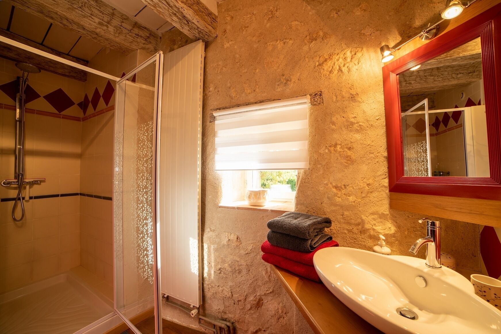 A bathroom with a shower, a sink, and a window.