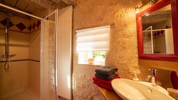 A bathroom with a shower, a sink, and a window.