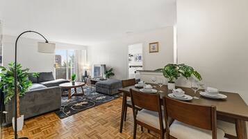 Ein modernes Wohnzimmer mit Sofa, Couchtisch und Esstisch, gedeckt für eine Mahlzeit.