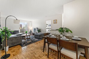 A modern living room with a sofa, coffee table, and dining table set up for a meal. - Gorgeous 2BR Next to BU f51x (Boston)
