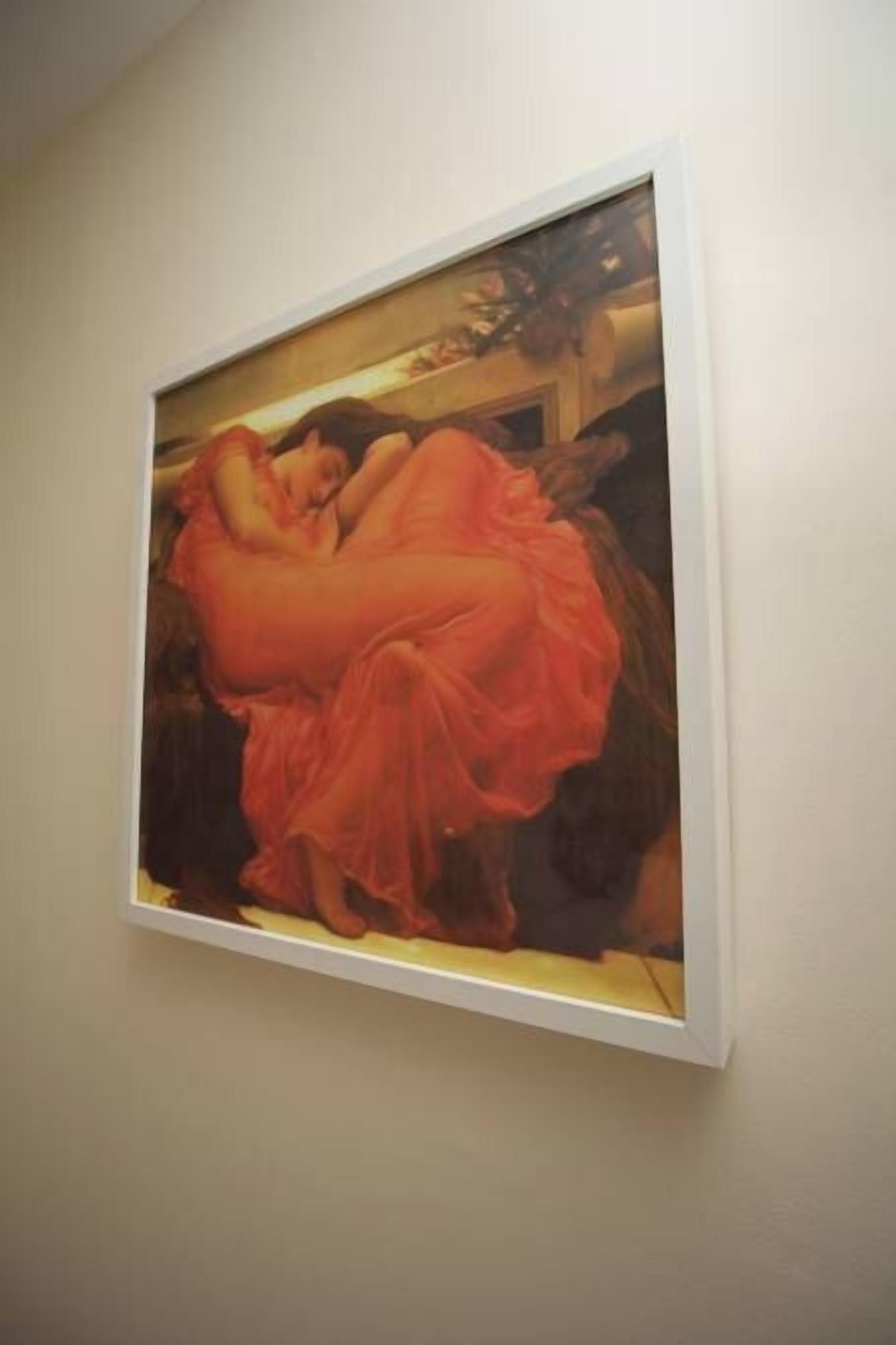 A framed painting of a woman in a flowing dress on a wall.