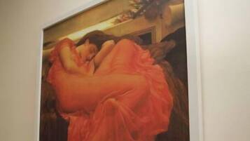 A framed painting of a woman in a flowing dress on a wall.