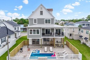 A two-story house with a backyard featuring a swimming pool, outdoor seating, and a fenced deck. - License To Chill-Pool, Put-put,Game Table, Slps 20 (North Myrtle Beach)