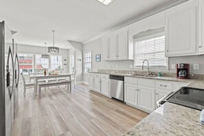 A modern kitchen with white cabinetry, a granite countertop, and a dishwasher. - License To Chill-Pool, Put-put,Game Table, Slps 20 (North Myrtle Beach)