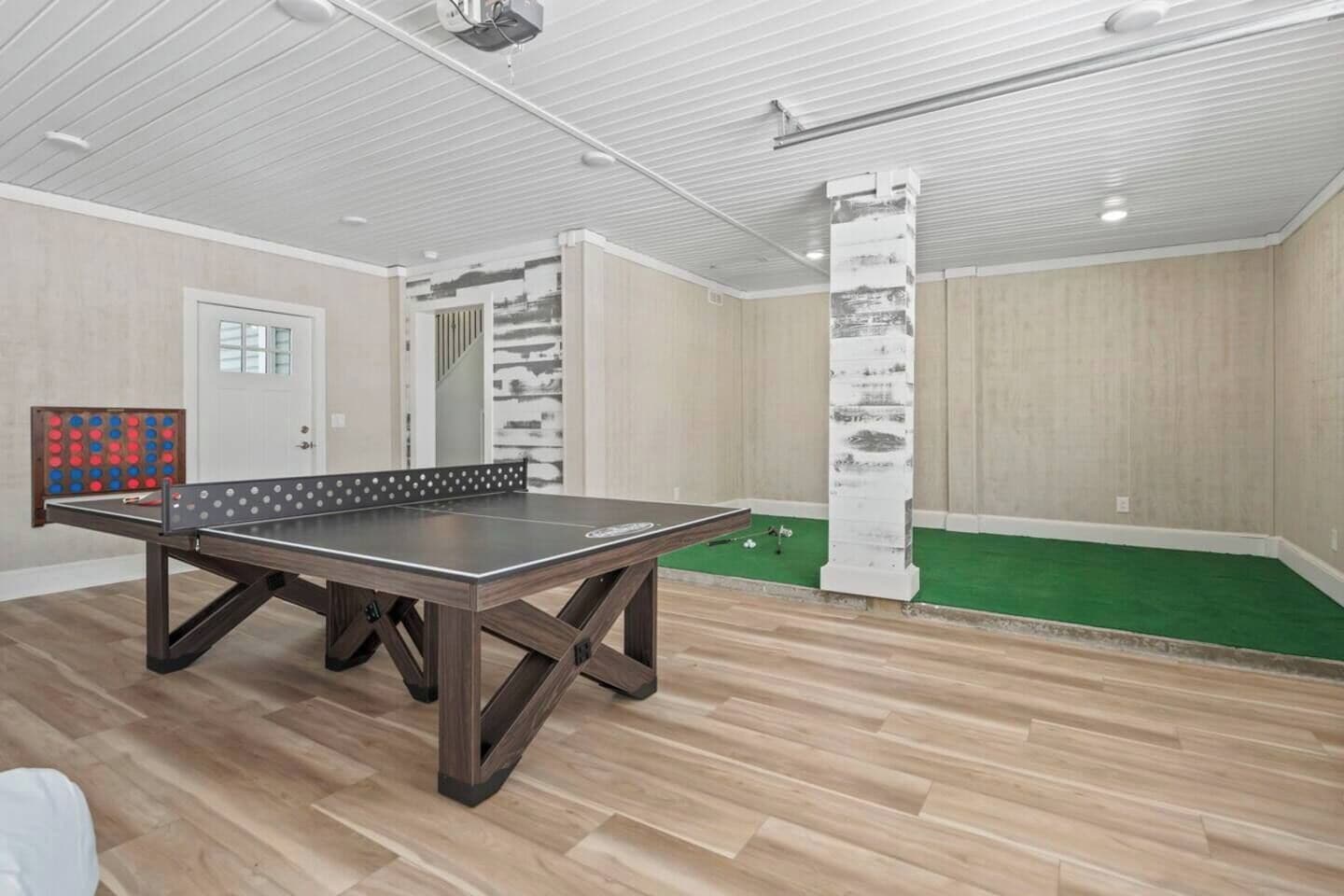 Ein Tischtennis-Tisch in einem Raum mit Holzboden, einer Tür und einer Wand mit einer vertikalen Holzwand.