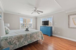 Une chambre à coucher avec un lit, une commode, un ventilateur de plafond et une fenêtre.