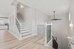 Un intérieur spacieux avec un escalier, un ventilateur de plafond et un coin cuisine.
