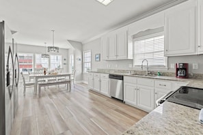 A modern kitchen with white cabinets, a granite countertop, and a built-in dishwasher.