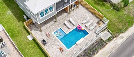 A two-story house with a swimming pool, outdoor seating, and a fenced yard.