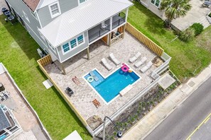 Une maison à deux étages avec une piscine, un espace extérieur aménagé pour s’asseoir et un jardin clôturé.