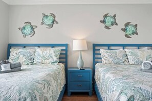 A bedroom with two beds, a nightstand, and decorative turtle wall art.