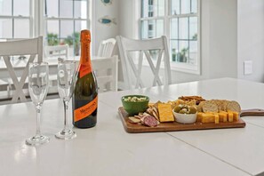 Une table avec une bouteille de Prosecco Monetto, deux verres et une planche de fromages accompagnée de divers fromages, d’olives et de crackers.