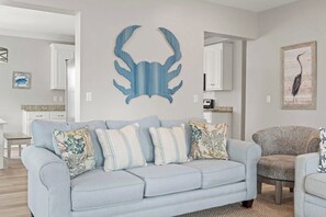 A living room with a light blue sofa, a patterned armchair, and a decorative wall piece.