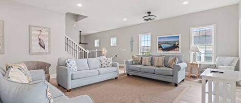 A spacious living room with two sofas, a coffee table, and a staircase.