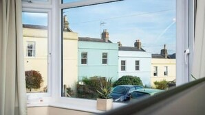 A window with a view of a row of colorful houses and a parked car. - Luxury Bath retreat with beautiful views! (Bath and North East Somerset)