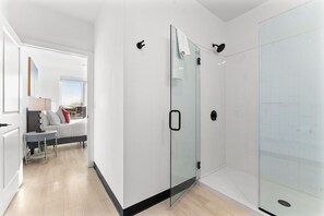 Une salle de bain moderne dotée d’une cabine de douche en verre, d’un espace de douche carrelé de carreaux blancs et d’une porte en verre.