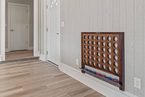 Un couloir avec un plancher en bois, des murs blancs et une porte. Un présentoir contenant des objets circulaires est fixé au mur.