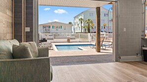 An open living area with a pool, outdoor furniture, and a view of a building with a white fence. - Epic 7BR Getaway - Pool, Game Room, Put-put, Beach (North Myrtle Beach)