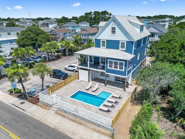 A two-story house with a swimming pool and a fenced deck area.