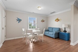 Une pièce comprenant une table à manger, des chaises, un canapé, une lampe et des autocollants décoratifs sur les murs.