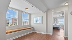 A room with a wooden bench, a ceiling fan, and a door leading to another room with a bed. - Epic 7BR Getaway - Pool, Game Room, Put-put, Beach (North Myrtle Beach)