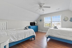Une chambre avec deux lits, un ventilateur de plafond, une télévision et une fenêtre donnant sur un paysage agréable.