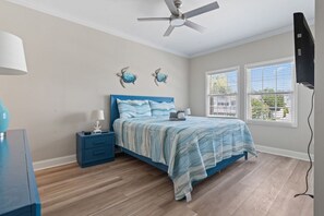 A bedroom with a bed, nightstands, a ceiling fan, and two windows with blinds.